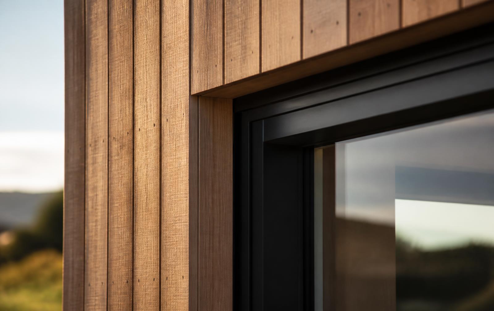 Close detail of cedar timber cladding meeting dark aluminium window joinery