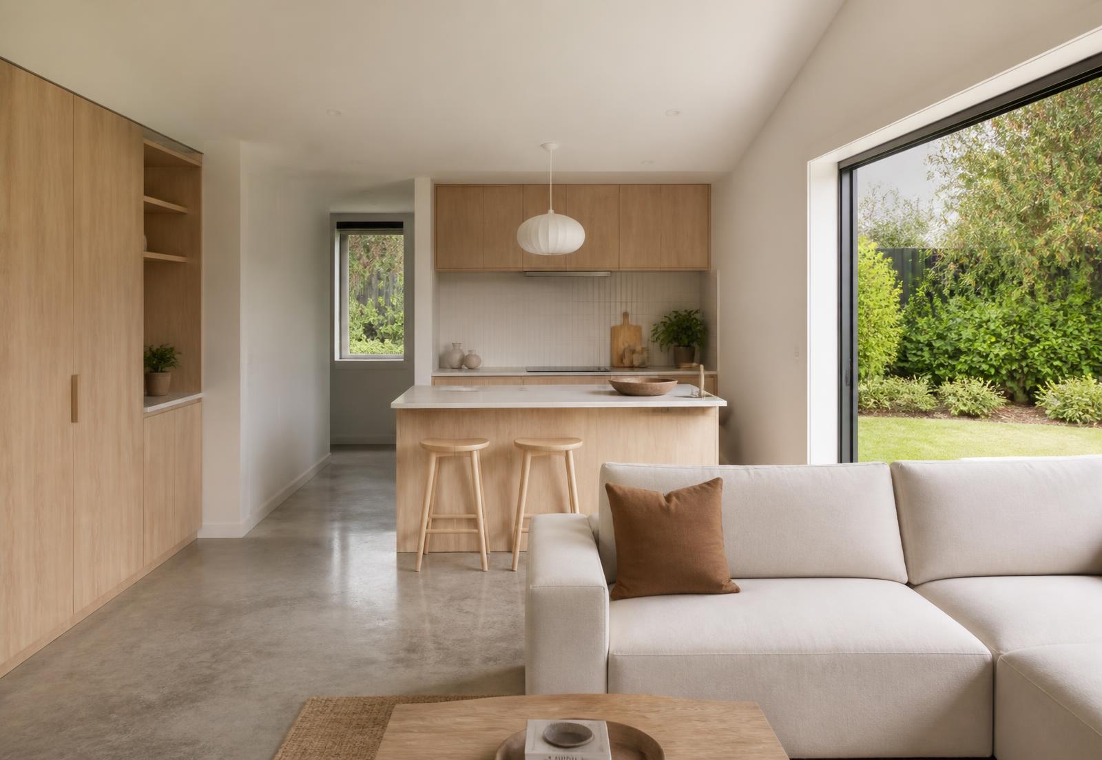 Interior of a small contemporary dwelling with pale oak kitchen joinery and a large window to the garden